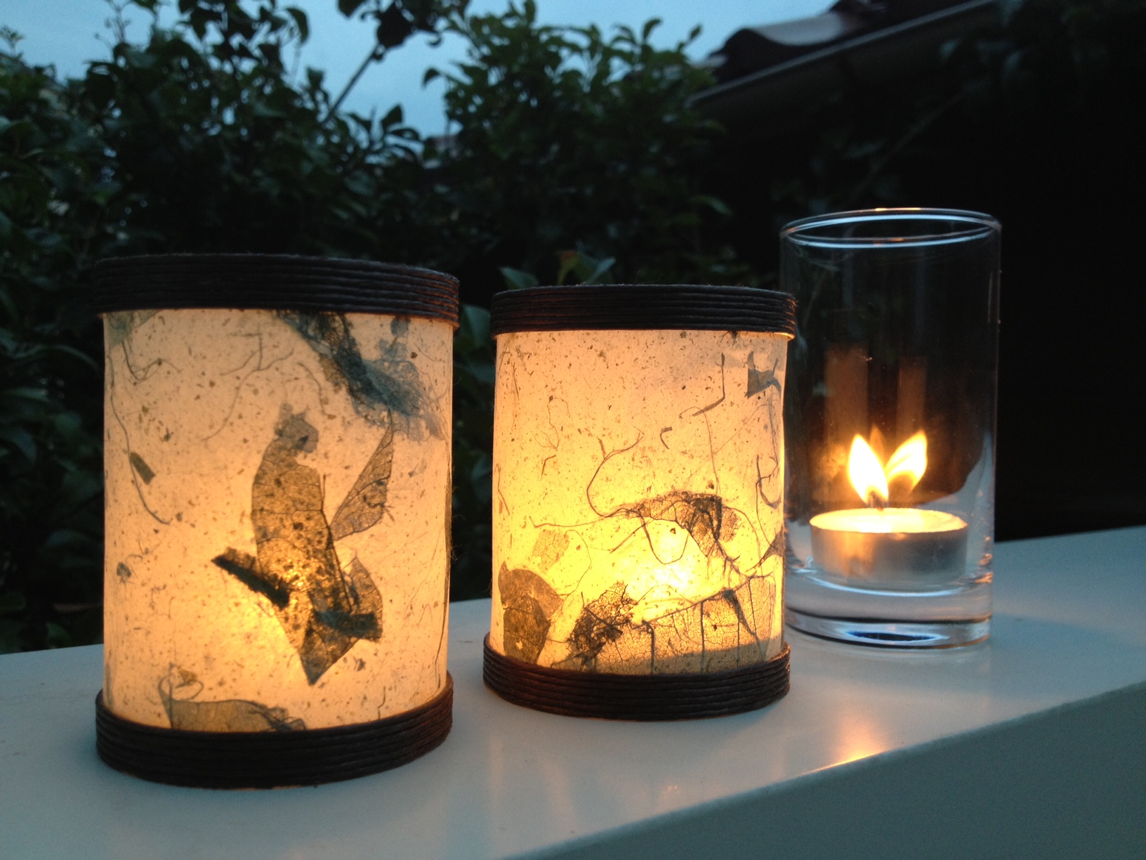 Deux lanternes en papier washi aux motifs de feuilles, lumière ambrée et chaude sur fond sombre