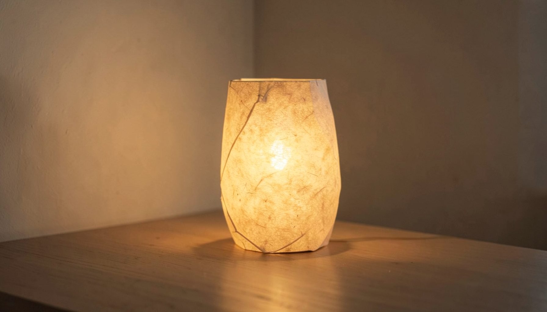 Lampe en papier washi diffusant une lumière chaude et tamisée dans une pièce sobre, ambiance apaisante